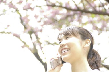 Parkta cep telefonu kullanan genç bir kadın.