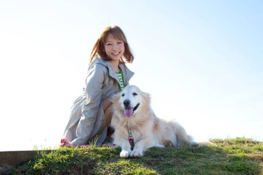 Parkta av köpeğiyle gezen güzel genç Japon kadın.
