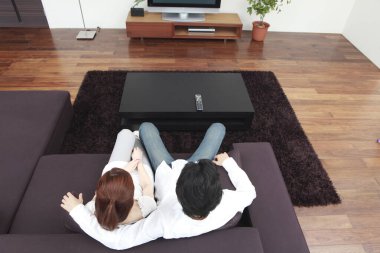 Kanepede oturup televizyon izleyen bir çift.