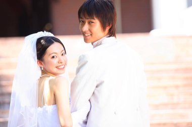 Dışarıda poz veren mutlu Asyalı bir çift yeni evli.