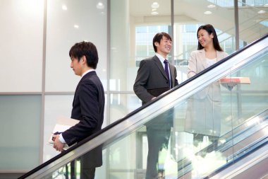 Ofiste yürüyen merdivendeki genç iş adamları.