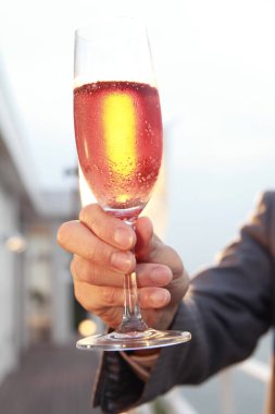 Adam şehrin arka planında şampanya kadehi tutuyor.