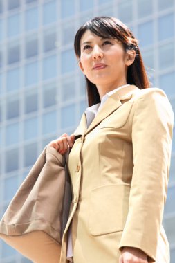 Ofis binasına karşı poz veren güzel Asyalı iş kadınının portresi.