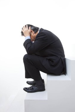 Depresyonlu takım elbiseli bir adam basamakta oturuyor.