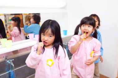 Anaokulu çocukları banyoda diş fırçalıyorlar. 