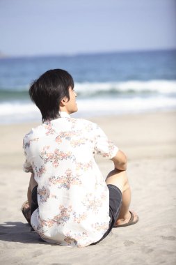 Deniz kıyısındaki genç bir adamın arka görüntüsü 