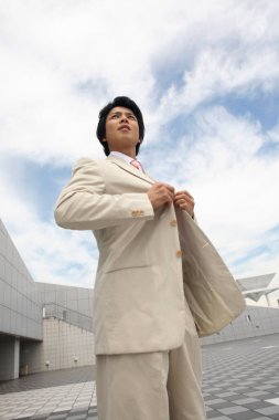 Takım elbiseli ve kravatlı bir adam sokakta dikiliyor. 