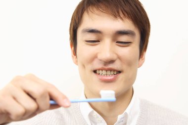 Diş fırçalı yakışıklı Japon adamın portresi.
