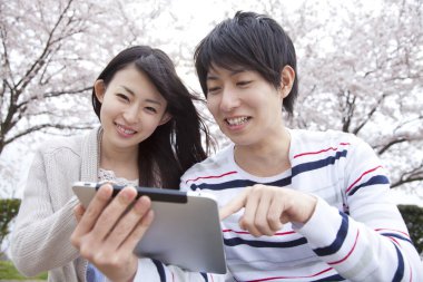 Park yerinde dijital tableti olan genç Japonlar