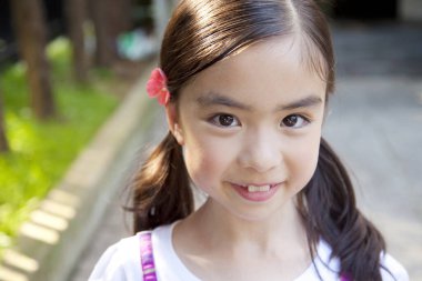 Kameraya gülümseyen Asyalı genç kızın portresi