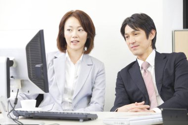 Bir adam ve bir kadın bilgisayar başında oturuyor.