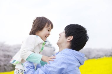 Küçük baba ve küçük oğlu bahar zamanı kolza tohumu tarlasında birlikte eğleniyorlar.