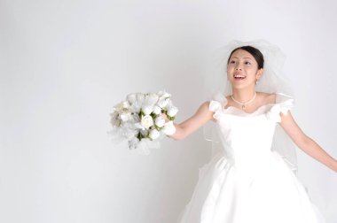 Asyalı gelinin elinde bir buket var.