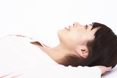 Genç Asyalı bir kadın yatakta yatıyor. 