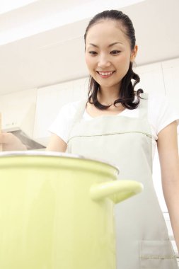 Güzel Asyalı ev hanımı mutfakta yemek pişiriyor.