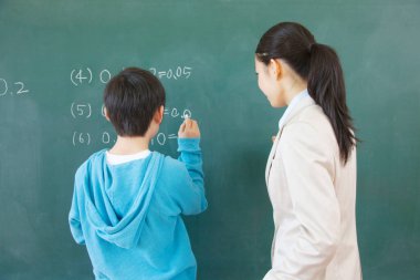 Asyalı bayan öğretmen ve okul çocuğu sınıftaki tahtada.