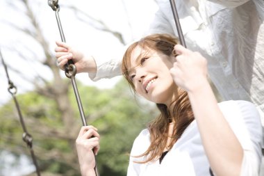 Asyalı kadın yeşil parkta sallanıyor.