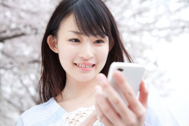 Parkta cep telefonu kullanan Asyalı kadın. 