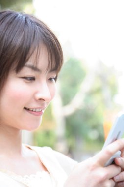 Dışarıda cep telefonu kullanan genç bir kadın.