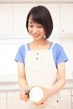 Güzel Asyalı ev hanımı mutfakta yemek pişiriyor.