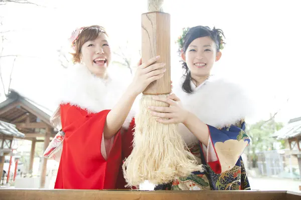 stock image Asian girls dressed in furisode shaking bell in temple after praying