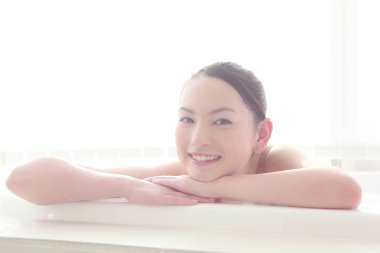 Genç Asyalı kadın banyoda dinleniyor.