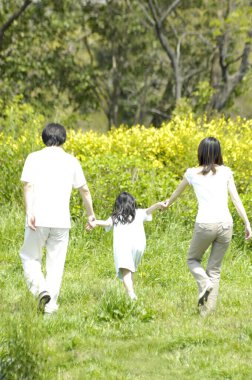 Tarlada yürüyen üç kişilik bir ailenin arka görüntüsü.