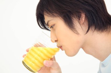 Genç Japon adam bardaktan meyve suyu içiyor.