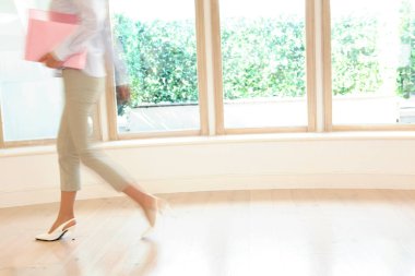 Belgeleri olan bir kadın ofiste yürüyor.