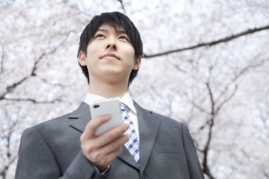 Parkta akıllı telefonu olan genç bir adam..