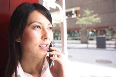 Bir kadın dışarıda dururken cep telefonuyla konuşuyor.