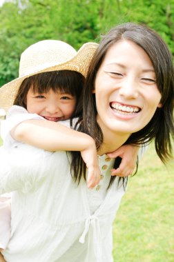 Genç bir kadın kızını sırtında taşıyor. 