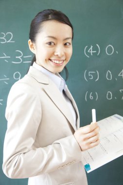 Sınıfta tahtaya yakın duran Asyalı matematik öğretmeni