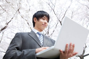 Dizüstü bilgisayarı olan Asyalı bir iş adamı.