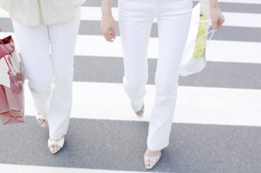 Sokakta alışveriş torbalarıyla yürüyen kadınlar 