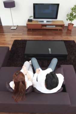 Bir çift televizyon karşısında kanepede oturuyor.