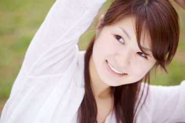 Parkta gülümseyen genç Asyalı kadın.