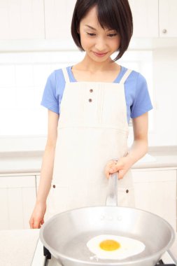 Güzel Asyalı ev hanımı mutfakta yemek pişiriyor.