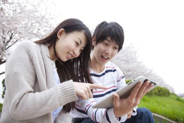 Park yerinde dijital tableti olan genç Japonlar