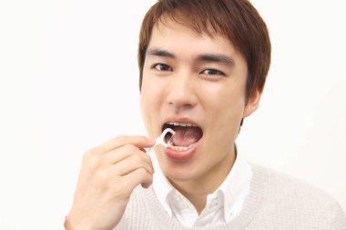 Dişleri temizlemek için diş ipi kullanan Japon 'un stüdyo portresi.
