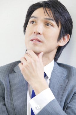 Genç Asyalı iş adamı düşünüyor ve araştırıyor.