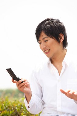 Bankta oturan bir adam cep telefonuna bakıyor.