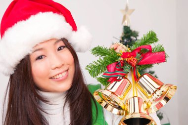 Noel Baba şapkalı Asyalı kadın Noel çanları taşıyor.