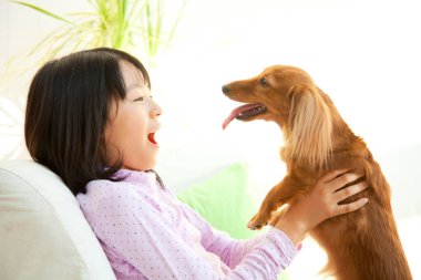 Evde dachshund tutan tatlı Japon kızın yan görüntüsü