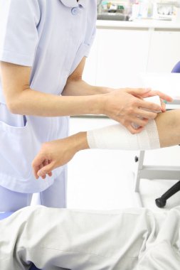 Hemşire erkek eline bandaj yapıyor.