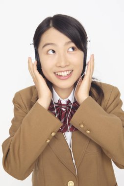 Genç Asyalı öğrenci kulaklıkla müzik dinliyor.