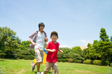 Asyalı genç adam oğluyla kamp alanında oynuyor.