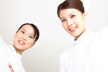 İki gülümseyen hemşire aşağıya bakıyor.