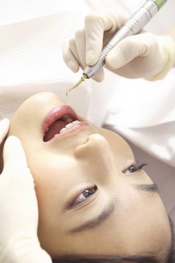 Genç Asyalı adam dişçi muayenehanesinde diş tedavisi görüyor.