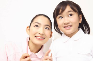 Japon kadın dişçi şirin küçük kıza diş fırçalamayı öğretiyor.